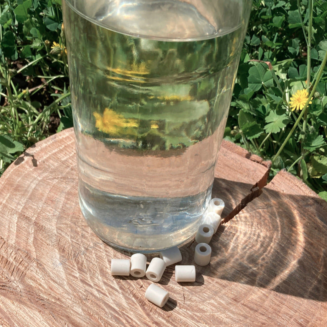 Perles de céramique purifiantes posées à côté d'une bouteille d'eau